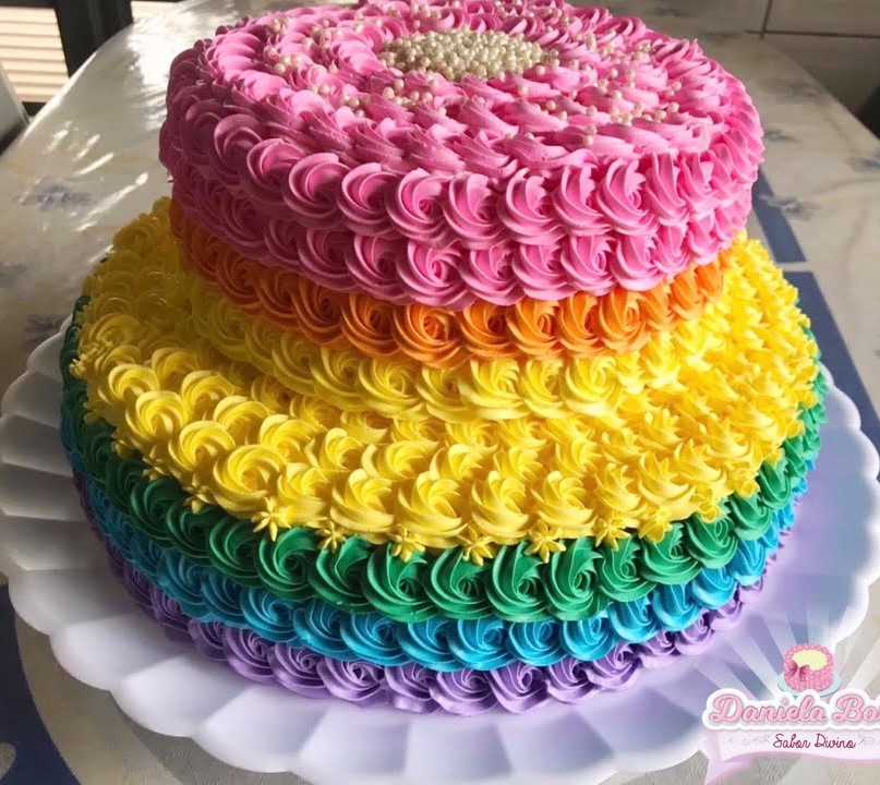 Um bolo roxo com glacê roxo e branco e um arco-íris no topo